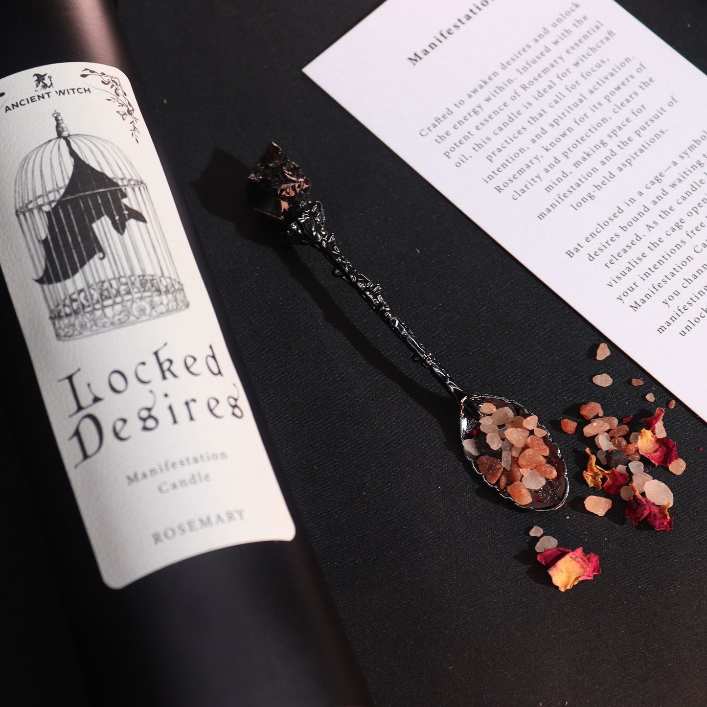 Bougie Désirs Enfermés et cuillère noire remplie de sels rituels devant la carte de rituel, détail du parfum romarin.