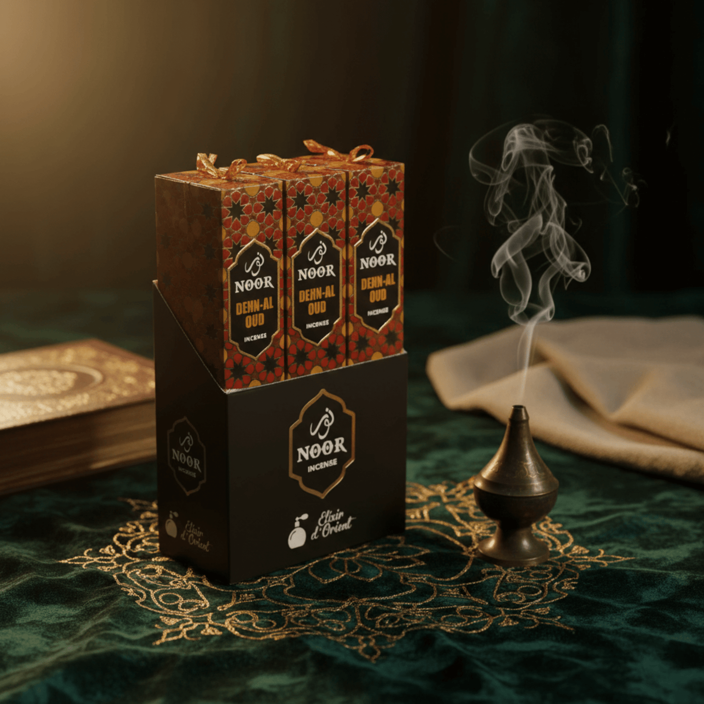 Boîte d’encens Noor Dehn Al Oud avec fumée parfumée, décor oriental luxueux sur tissu vert sombre.