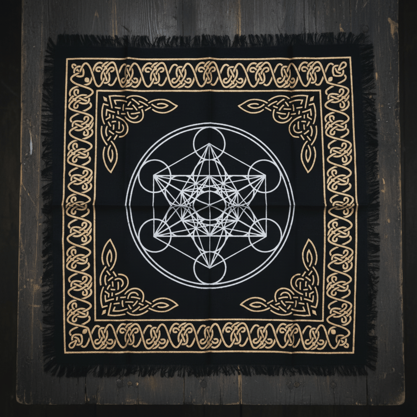 Vue rapprochée d’une nappe noire à symbole du cube de Métatron et bordure celtique sur table sombre.