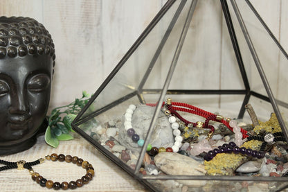 Bracelets lithothérapie dont Jaspe Dalmatien, Oeil de Tigre et Quartz Rose, exposés dans une pyramide décorative zen.