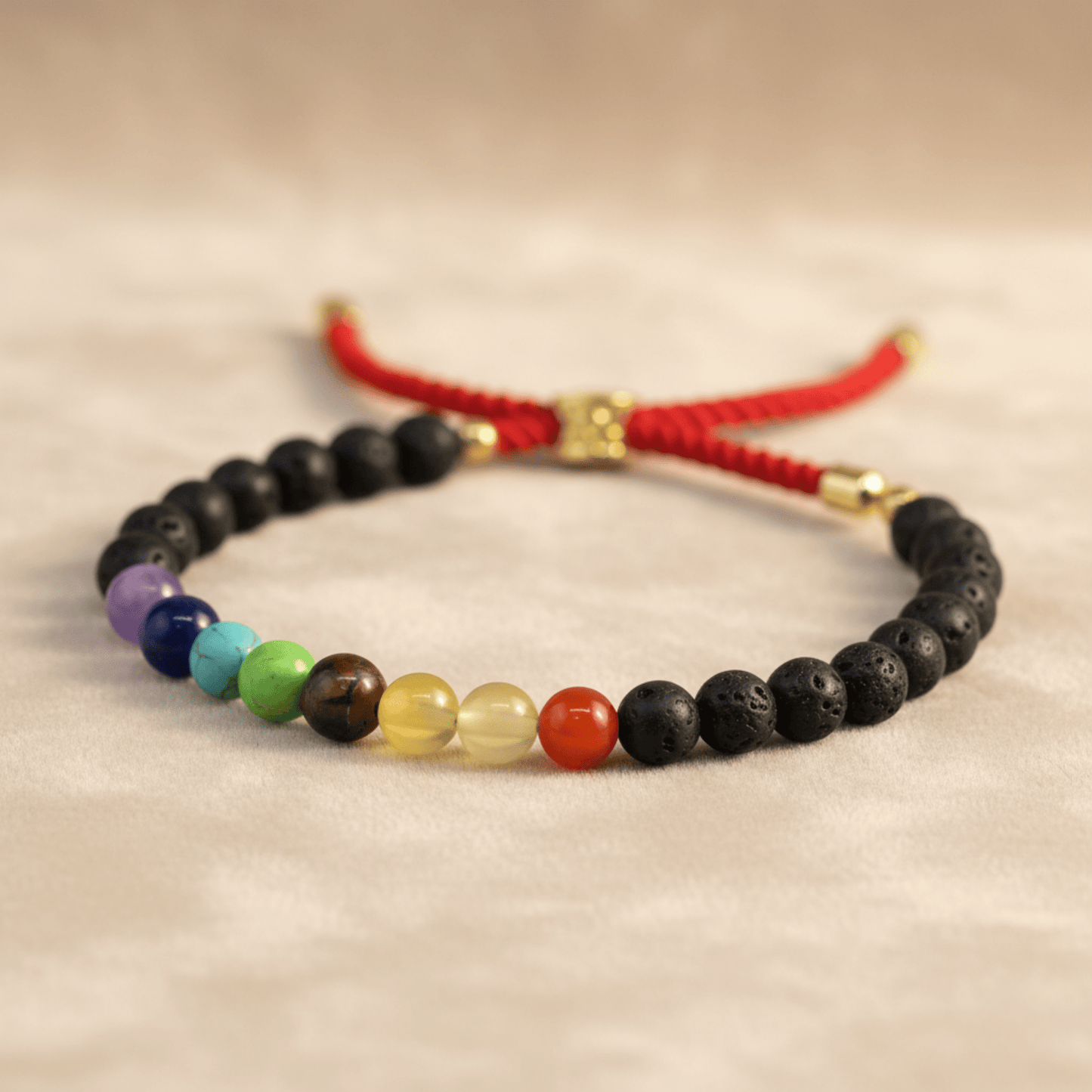 Bracelet pierre de lave volcanique avec perles chakra multicolores et cordon rouge.