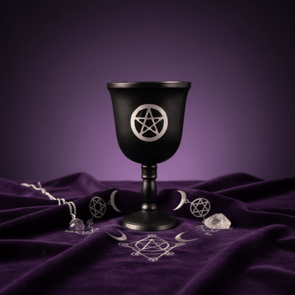 Calice pentacle noir pour rituels wiccans, exposé sur tissu violet avec symboles ésotériques et cristaux.