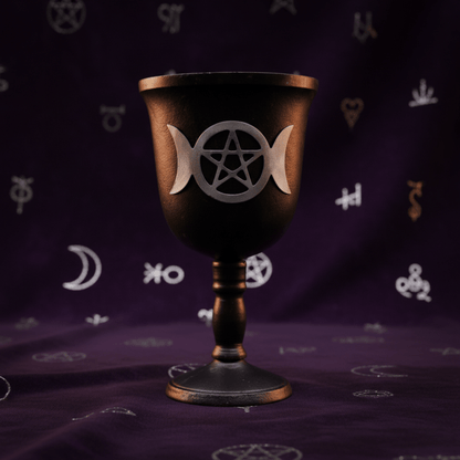 Calice rituel en fer noir avec symbole Triple Lune et pentacle, posé sur tissu violet ésotérique.