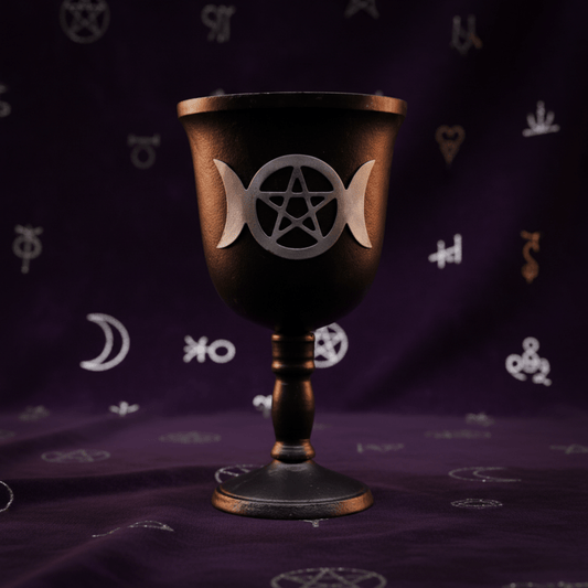 Calice rituel en fer noir avec symbole Triple Lune et pentacle, posé sur tissu violet ésotérique.