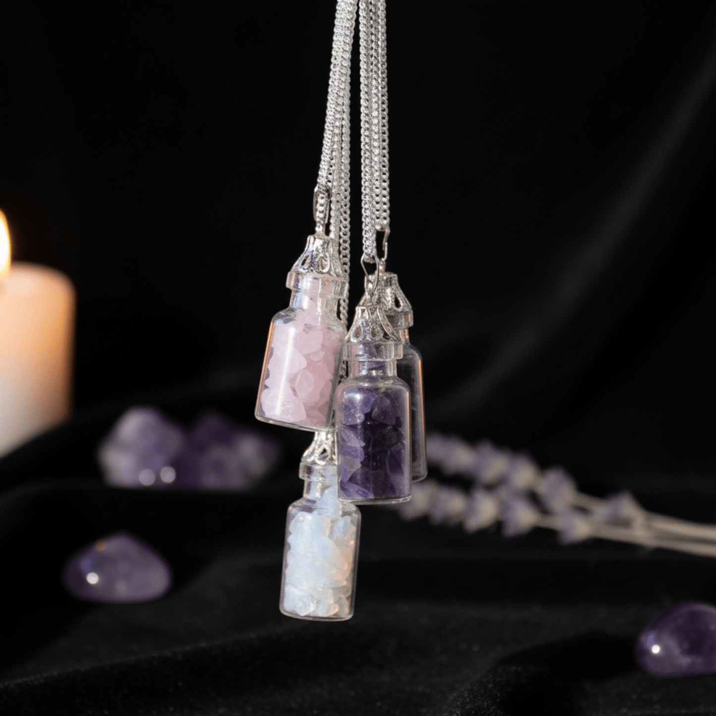 Trois colliers bouteilles en pierres naturelles suspendus : quartz rose, améthyste et opalite.