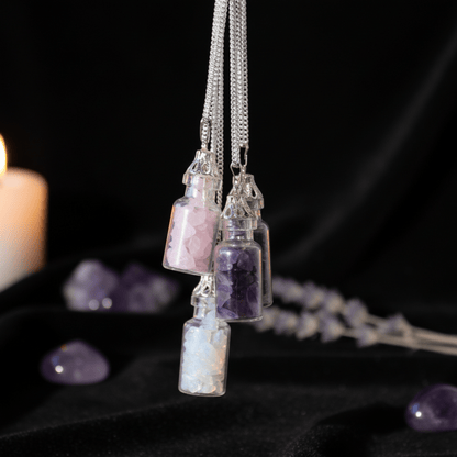 Trois colliers bouteilles en pierres naturelles suspendus : quartz rose, améthyste et opalite.