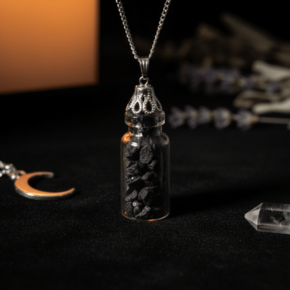Collier bouteille avec fragments d’onyx noir dans une fiole en verre sur fond sombre.