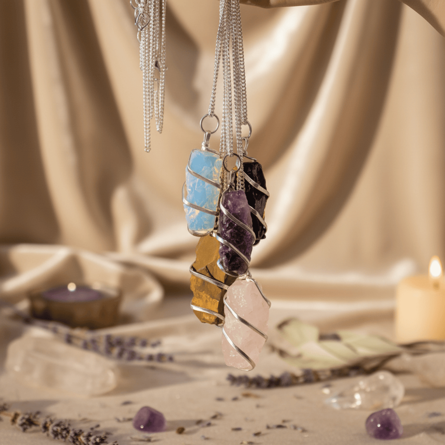 Collection de pendentifs en pierres naturelles brutes, dont quartz rose, suspendus dans ambiance spirituelle.