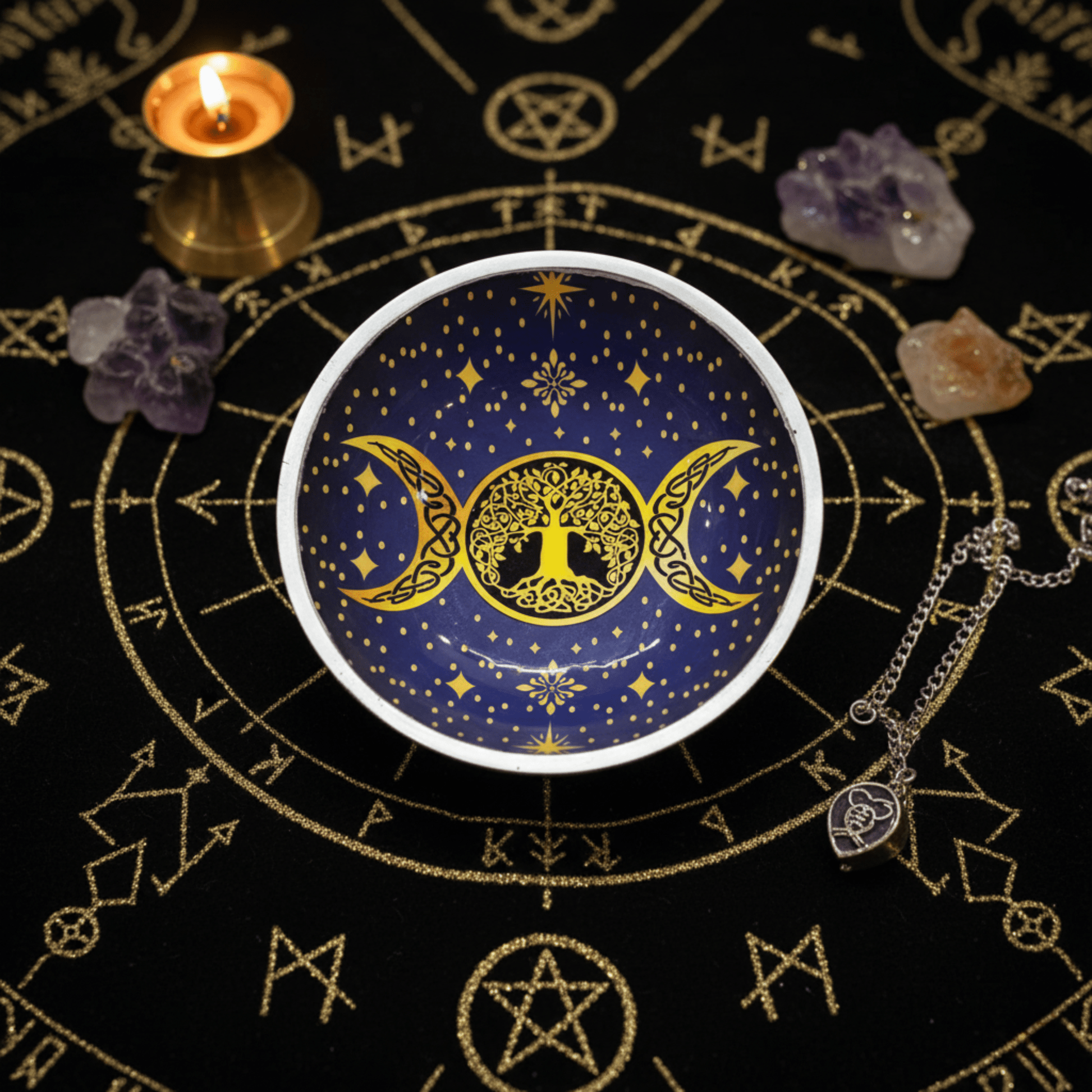 Coupe ésotérique Triple Lune bleu et or, motif Arbre de Vie, entourée de cristaux et bougie sur un tissu rituel ornementé.