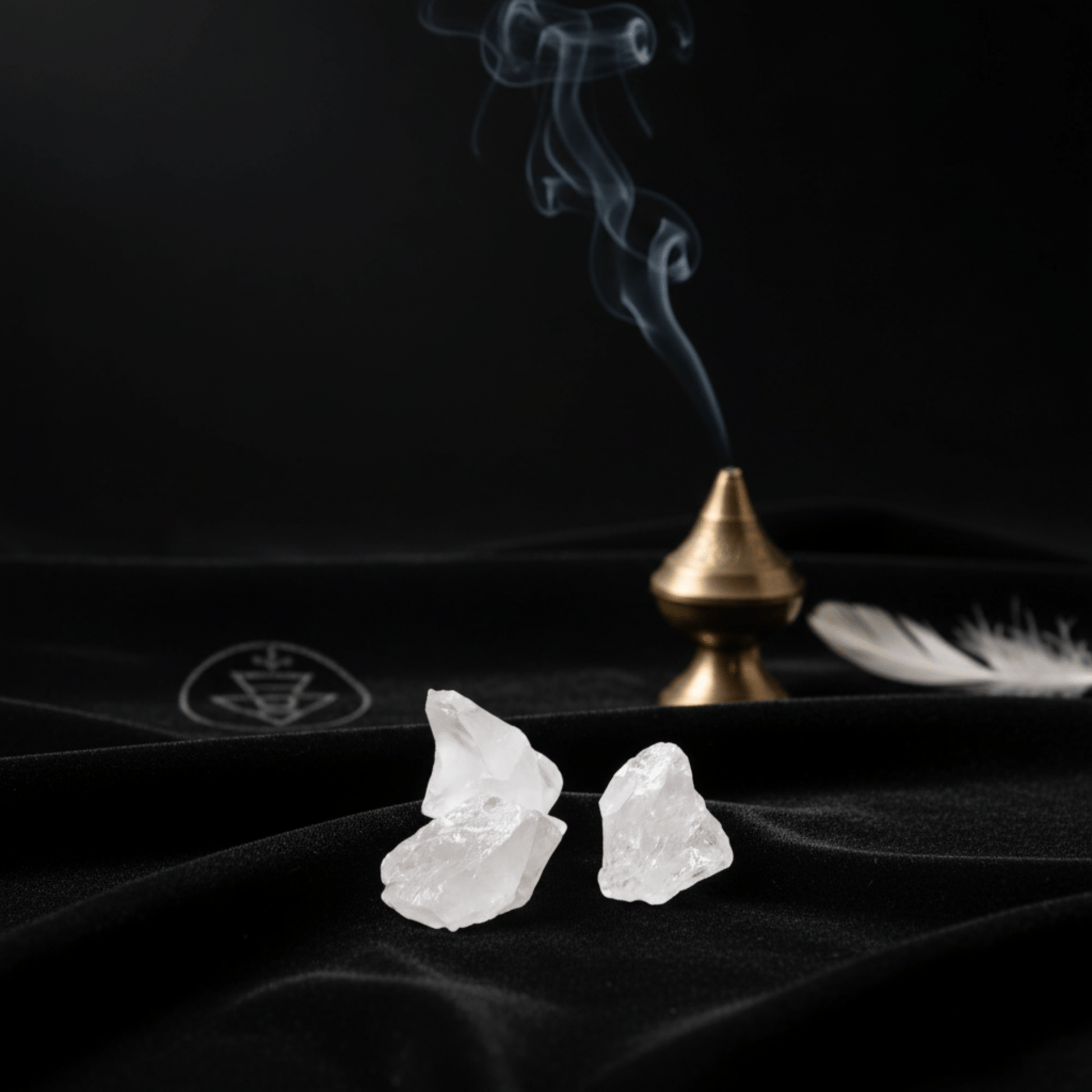 Cristaux de roche brut sur tissu noir avec fumée d’encens, pierre de lumière et de clarté spirituelle.