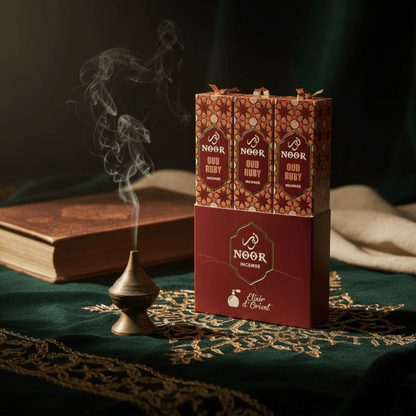 Boîte d’encens Noor Ruby avec fumée mystique, ambiance orientale et tissu vert doré luxueux.