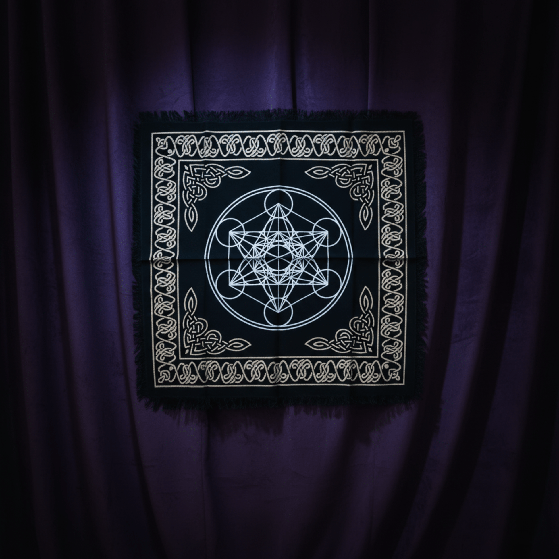 Nappe d’autel noire avec motif du cube de Métatron et bordures celtiques, suspendue sur rideaux violets.