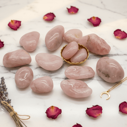 Quartz rose poli sur fond marbré avec pétales de rose, pierre d’amour et de guérison émotionnelle.