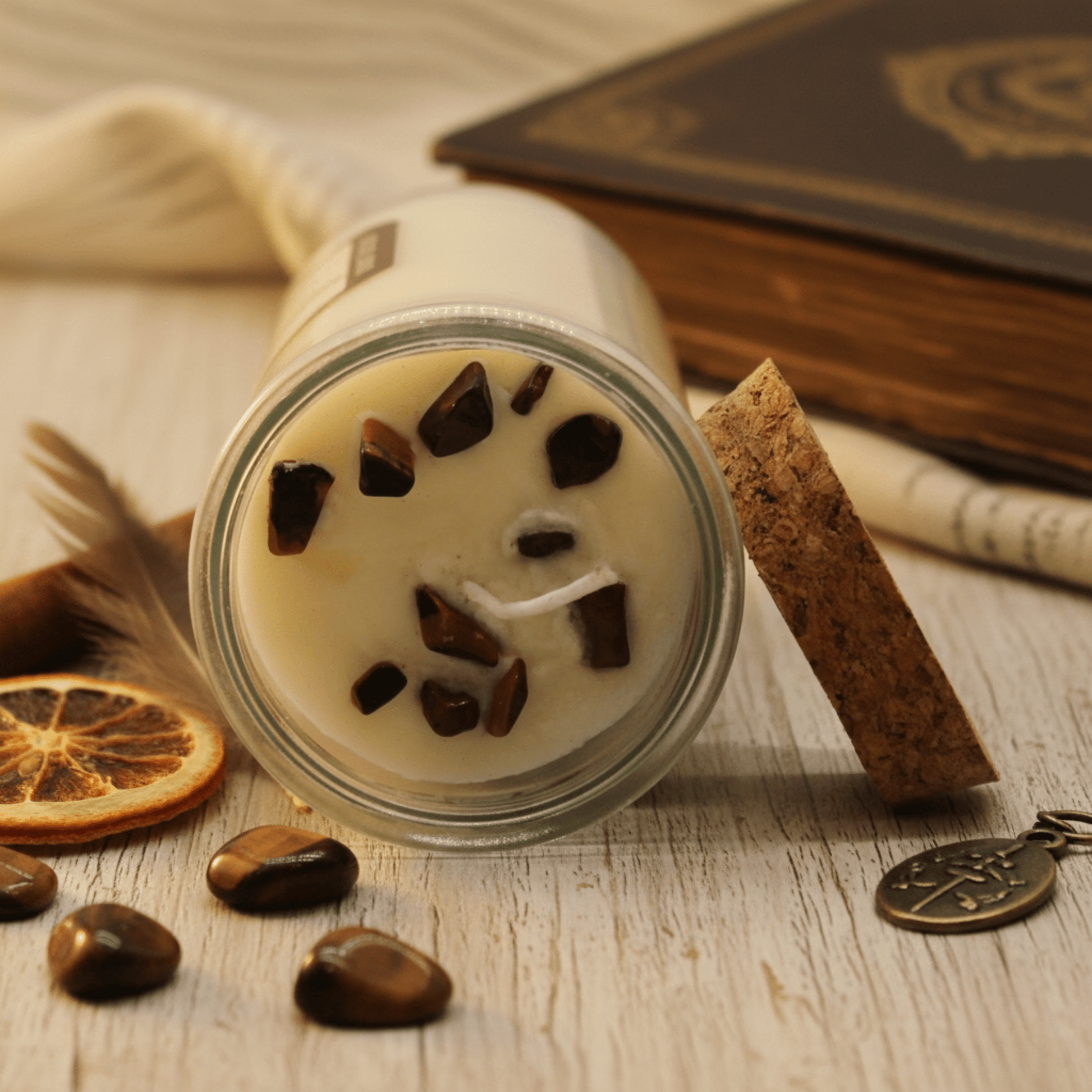 Vue rapprochée d’une bougie rituelle ornée de pierres œil-de-tigre incrustées dans la cire de soja.