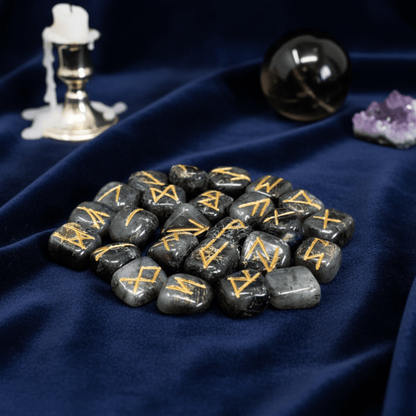 Set de runes en labradorite gravées or, pierres de divination pour protection et magie, posé sur tissu bleu mystique.